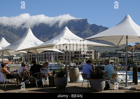 Holidaymakers drinking & eating on the V&A Waterfront on Cape town Harbour overlooked by Table Mountain Stock Photo