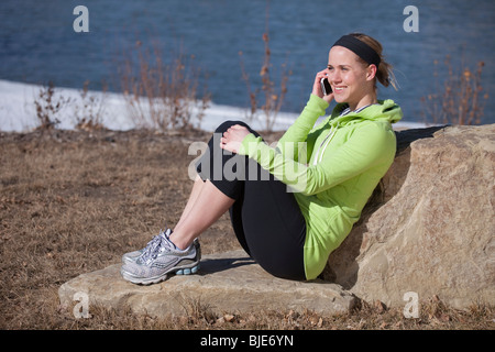 Smiling cheerful woman in casual clothing talking on iPhone outdoors Stock Photo
