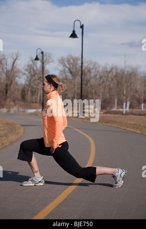 Woman runner stretching on a path in city park Stock Photo