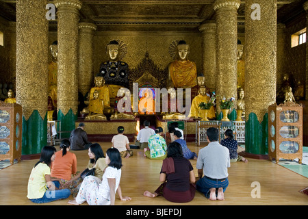 Burmese people praying in front of Buddha statues. Shwedagon Paya. Yangon. Myanmar Stock Photo