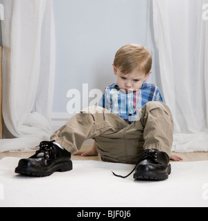 little boy wearing a man's shoes Stock Photo