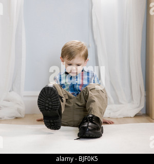 little boy wearing a man's shoes Stock Photo