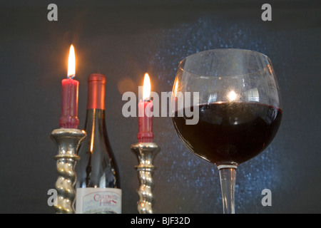 A bottle and wine glass of Pinot noir and candles burning in a romantic setting Stock Photo