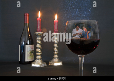 A bottle and glass of Pino noir and candles burning in a romantic setting Stock Photo