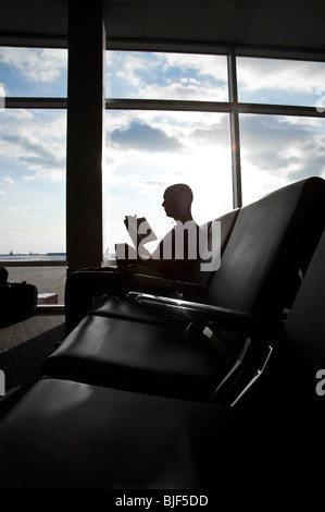 Man In Airport Lounge Waiting Area Reading Book In Front Of Large Window, Philadelphia, USA Stock Photo