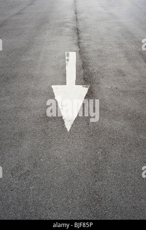 Arrow Pointing Down painted on a Tarmac road Stock Photo