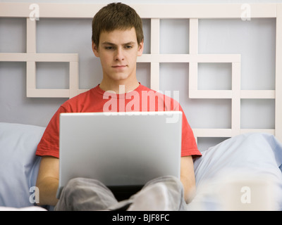 man working on a laptop on a bed Stock Photo