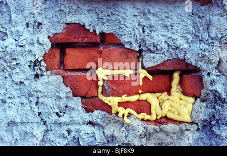 Foam insulation inbetween exposed brick in an alleyway. Stock Photo