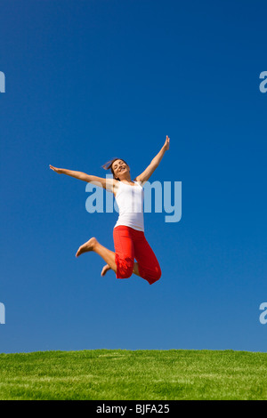 Beautiful young woman jumping on a green meadow Stock Photo