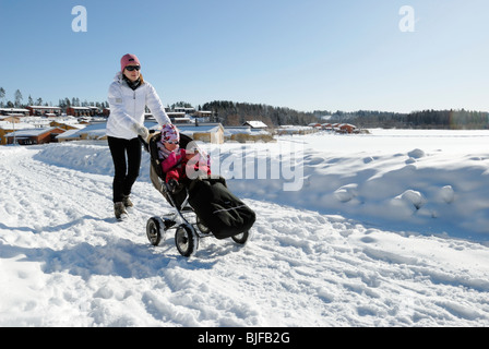 Mum on a walk with two kids in a pram Stock Photo