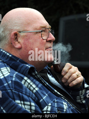 Old man smoking a pipe in his back garden Stock Photo