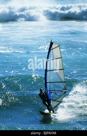 Windsurfer in action on the ocean against crashing waves Stock Photo