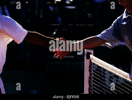 Tennis players shaking hands over the net Stock Photo