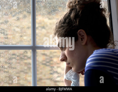 Sad/depressed young woman by rainy window: MODEL RELEASED Stock Photo