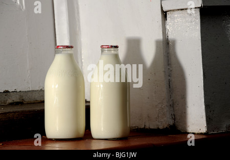 Glass Bottles of milk on a doorstep delivered by milkman UK Stock Photo