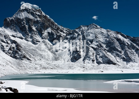 High snow capped mountain over icy lake, Himalayas, Nepal. Stock Photo