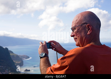 A man photographs the coast using a compact digital camera on the island of Madeira, Portugal. Stock Photo