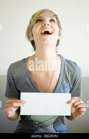 woman sitting on a couch holding up an envelope Stock Photo