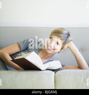 woman reading a book on the couch Stock Photo