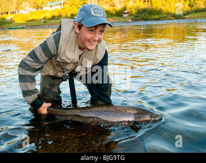NEW BRUNSWICK, Happy teenage male fly fisherman releasing Atlantic Salmon on the Miramichi River Stock Photo
