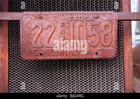 A rusted farm license plate on a rusting out antique car in Nebraska, USA. Stock Photo