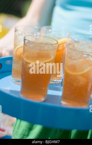 Person serving several glasses of iced tea on a tray - Stock Photo