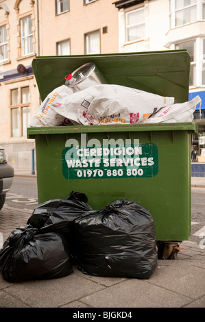 A green wheelie bin overflowing with commercial waste, Aberystwyth Ceredigion WALES UK Stock Photo