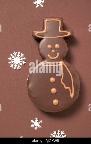 Snowman biscuit with chocolate icing on brown background - Stock Photo