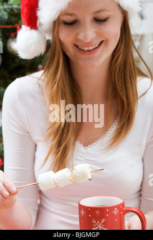 Woman in Father Christmas hat with marshmallows & cup of cocoa - Stock Photo