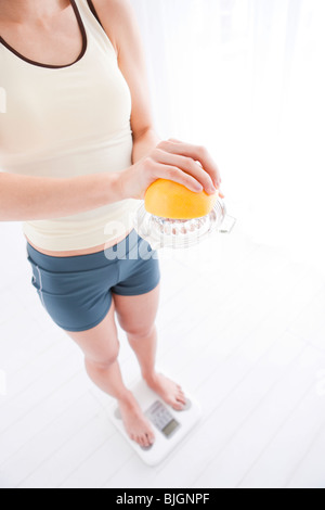 Woman weighing herself on bathroom scales Stock Photo