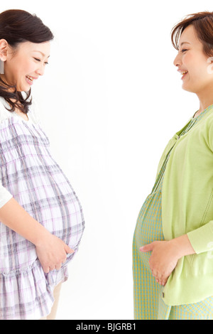 Studio portrait of two pregnant women standing facing each other Stock Photo