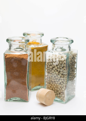 Nutmeg, turmeric, white peppercorns in spice bottles - Stock Photo