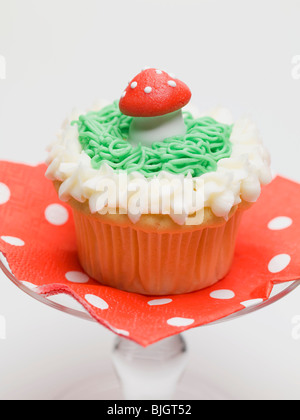 Muffin with fly agaric mushroom on cake stand - Stock Photo
