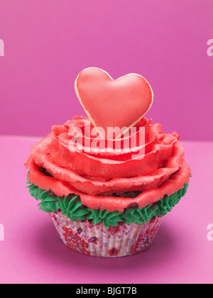 Cupcake with red marzipan rose and red pastry heart - Stock Photo