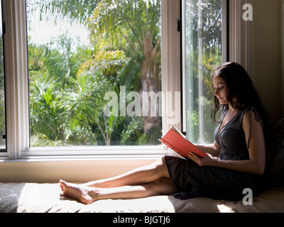 woman reading on a window bench Stock Photo
