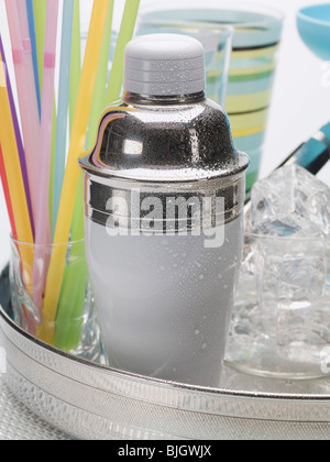 A cocktail shaker, ice cubes, glasses and straws - Stock Photo