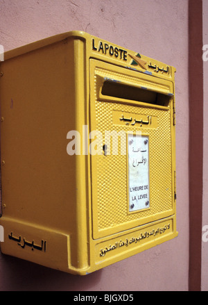 A yellow letterbox on wall of La Poste du Maroc, Morocco, Africa, with writing in both French and Arabic. Stock Photo