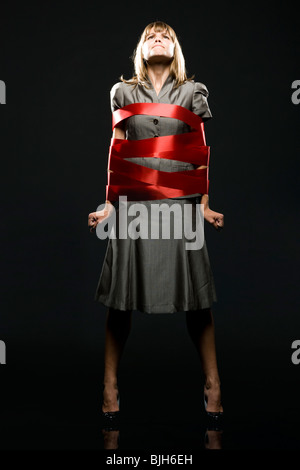 businesswoman all wrapped up in red ribbon Stock Photo