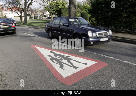 Children crossing warning pained on road showing 2 schoolchildren holding hands as a warning to drivers Stock Photo