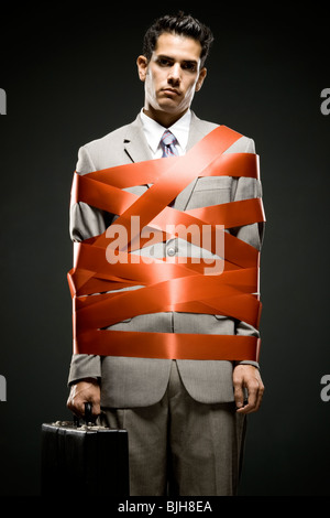 businessman wrapped up with red tape Stock Photo