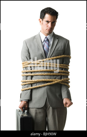 businessman in a full suit tied up with a rope around his mid section Stock Photo