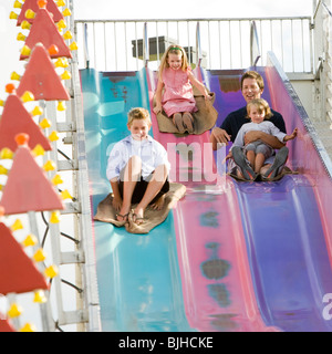 family at the carnival riding on the fun slide together Stock Photo