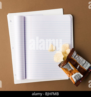 notebook with a bag of chips spilled onto an empty page Stock Photo