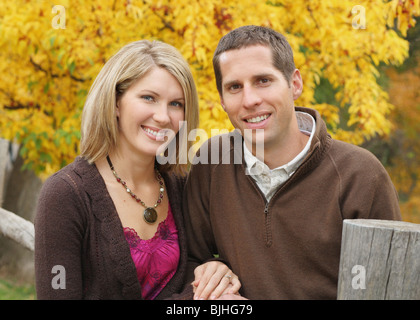 attractive couple standing together against bright yellow background in fall Stock Photo