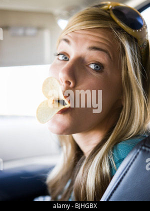 woman making duck lips with potato chips in her mouth Stock Photo