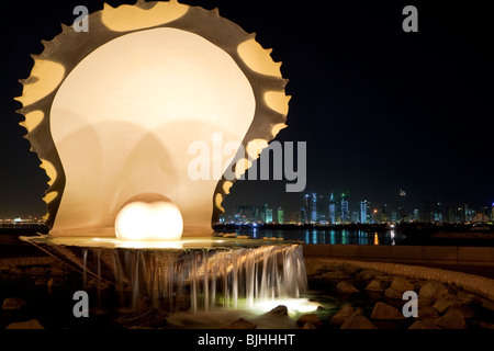 The Pearl and Oyster fountain on the Corniche in Doha, Qatar at night. The Doha skyline is visible in the background. Stock Photo