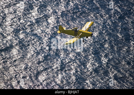 Small airplane ascending over water Stock Photo