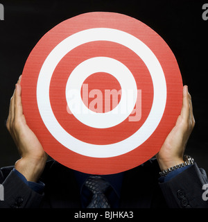 man holding a red target in front of his face Stock Photo