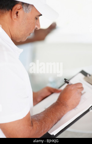 Repair person writing on clipboard Stock Photo