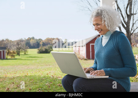 Woman working on laptop on porch Stock Photo